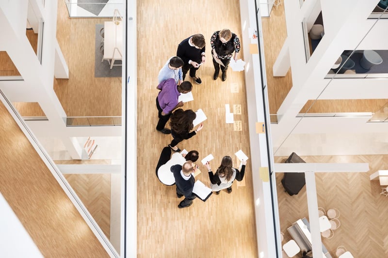 Ylhäältä kuvattu työryhmän kokoontuminen toimistotilassa